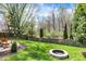A backyard includes a brick fire pit, manicured lawn, a wooden fence, and mature trees for private outdoor enjoyment at 3466 Firethorn Dr, Whitestown, IN 46075