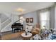 Elegant living room featuring a grand piano and staircase, complemented by neutral decor and abundant natural light at 3466 Firethorn Dr, Whitestown, IN 46075