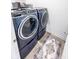 Laundry room featuring a modern blue washer and dryer set with a decorative rug on the tiled floor at 360 Lincoln W Cir, Fortville, IN 46040