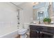 Bathroom featuring a bathtub, shower combo, dark vanity, and plant accent at 4917 Melbourne Rd, Indianapolis, IN 46228