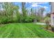 Spacious backyard with lush green grass, mature trees, and a stone fireplace at 5212 Knollton Rd, Indianapolis, IN 46228