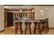 Open bar seating area featuring wooden barstools and light fixtures, with a kitchen area in the background at 553 Bolderwood Ln, Carmel, IN 46032