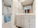 Well-lit bathroom featuring a white vanity, framed mirror, and blue tiled shower with glass door at 553 Bolderwood Ln, Carmel, IN 46032
