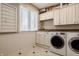 Bright laundry room featuring white cabinets, tiled floor, and modern washer and dryer at 553 Bolderwood Ln, Carmel, IN 46032
