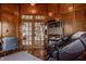 Wood paneled office features a desk, massage chair, shelving and glass french doors to the foyer at 553 Bolderwood Ln, Carmel, IN 46032