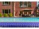 Beautiful in-ground pool with an umbrella covered seating, surrounded by lush landscaping and a grand brick home at 553 Bolderwood Ln, Carmel, IN 46032
