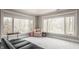 A bright sitting area with large windows offering natural light and views of nature and a comfortable black leather sofa at 553 Bolderwood Ln, Carmel, IN 46032