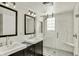 Bathroom featuring double sinks, mirrors, subway tile shower with glass door, and gray tile flooring at 5611 N Delaware St, Indianapolis, IN 46220