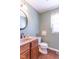 Powder room with a vanity, round mirror, toilet, and wood-style floor at 5895 Sugar Pine Dr, Avon, IN 46123