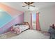 Bedroom with a ceiling fan, window view, and an eye-catching painted accent wall at 6536 W Shoreline Ct, Greenfield, IN 46140