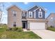 Charming two-story home with blue and brick exterior, complemented by a well-manicured lawn and an attached two-car garage at 6536 W Shoreline Ct, Greenfield, IN 46140