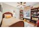 Cozy bedroom featuring hardwood floors, a ceiling fan, built-in bookshelves, and a sunlit window seat at 6853 Arjay Dr, Indianapolis, IN 46217
