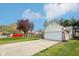 Suburban home with two-car garage, long driveway, a green lawn and mature trees at 6853 Arjay Dr, Indianapolis, IN 46217