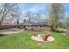 Brick home featuring a fire pit with chairs, solar panels, and expansive green lawn at 8051 Sycamore Springs Trl, Indianapolis, IN 46239