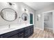 Bathroom featuring double vanity, round mirrors, elegant fixtures, white walls, and wood-look floors at 8850 W 225 S, Columbus, IN 47201