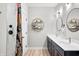 Bright bathroom featuring double vanity, round mirrors, elegant fixtures, and a decorative shower curtain at 8850 W 225 S, Columbus, IN 47201