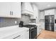 Well-lit kitchen boasts modern appliances, white cabinetry, gray backsplash, and hardwood floors at 8850 W 225 S, Columbus, IN 47201