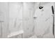 Modern walk-in shower with white marble tile, a built-in bench, and a sleek black shower head at 8850 W 225 S, Columbus, IN 47201