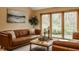 Cozy living room with a comfortable brown leather couch, accent pillows, and lush view of the landscape at 8901 Shetland Ln, Indianapolis, IN 46278