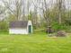 A backyard shed offers storage space on a well-kept lawn that extends to the edge of wooded acreage at 9243 Compton Farm Ln, Indianapolis, IN 46259