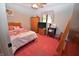 Cozy bedroom with red carpet, wood furniture, and a colorful floral bedspread at 1000 Riverview Dr, Martinsville, IN 46151