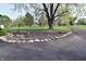 Landscaped front yard with mature tree, rock border, driveway, and flowering plants at 1000 Riverview Dr, Martinsville, IN 46151