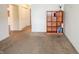 A bright, neutral living room featuring beige carpet and a wooden bookshelf against a white wall at 10822 Cape Coral Ln, Indianapolis, IN 46229