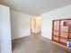 Neutral living room featuring beige carpet and a wooden bookshelf against a white wall at 10822 Cape Coral Ln, Indianapolis, IN 46229