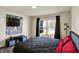Bedroom with wood floors, a large TV, and a window providing natural light and neighborhood views at 11603 Presidio Dr, Indianapolis, IN 46235