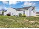 Back exterior view showcasing a tidy yard, neutral siding, and mature shrubbery at 11603 Presidio Dr, Indianapolis, IN 46235