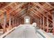 Unfinished attic space with exposed rafters, wooden beams, and a window, offering potential for storage or expansion at 1231 Nester St, Speedway, IN 46224