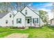 Charming home with white siding, green trim, well-manicured lawn, and vibrant landscaping at 1231 Nester St, Speedway, IN 46224