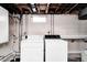 Basement laundry area with white washer and dryer, utility sink, and exposed pipes at 1231 Nester St, Speedway, IN 46224