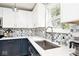 Close up of the kitchen with white cabinets, blue backsplash, a stainless steel sink, and modern faucet at 12981 Coyote Run, Fishers, IN 46038