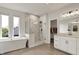 Bright bathroom featuring a soaking tub, glass shower, and vanity with views from the windows at 14349 Marsdale Pl, Carmel, IN 46074