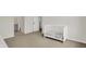 Bright bedroom with neutral carpet, white trim, and a crib, offering a cozy and serene space at 14349 Marsdale Pl, Carmel, IN 46074