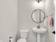 Modern powder room with a pedestal sink, round mirror, and stylish decor at 14349 Marsdale Pl, Carmel, IN 46074