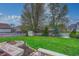 Spacious backyard with lush green lawn, mature trees, storage shed, and fire pit area at 1910 Riverstone Ct, Westfield, IN 46074