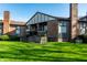 View of a two-story brick home featuring a balcony and a fenced-in patio surrounded by a lush green lawn at 2141 Rome Dr # Apt B, Indianapolis, IN 46228