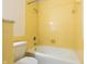 A classic bathroom with bright yellow tiling and a white bathtub, toilet, and marble detailing at 2141 Rome Dr # Apt B, Indianapolis, IN 46228