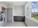 A well-lit laundry room featuring a sink, dark cabinets, and a washer beside a bright window at 284 Chatham Hills Blvd, Westfield, IN 46074