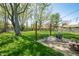 Spacious backyard featuring a large tree, a patio with a fire pit and a partially fenced lawn at 3615 Dawnwood Dr, Indianapolis, IN 46227