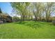 Spacious backyard featuring lush lawn, mature trees, wooden deck, and a firepit area, perfect for outdoor gatherings at 3615 Dawnwood Dr, Indianapolis, IN 46227
