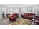 Bright living room features hardwood floors, large windows, and comfortable red leather seating at 400 E Charter Dr, Muncie, IN 47303