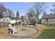 Inviting backyard features a cozy fire pit, a charming wooden deck, and mature trees, perfect for outdoor entertaining at 413 Vasbinder Dr, Anderson, IN 46017