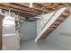 Basement with utility access, wooden stairs, and essential services neatly arranged at 4814 Southeastern Ave, Indianapolis, IN 46203