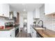 Modern kitchen featuring white cabinets, a tile backsplash, and a view to the living room at 4814 Southeastern Ave, Indianapolis, IN 46203