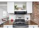Stylish kitchen with stainless steel appliances, wood countertop, and brick accent wall at 4814 Southeastern Ave, Indianapolis, IN 46203
