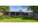 A level, grassy backyard with mature trees and a brick house with a covered patio at 5444 S Holiday Dr, Columbus, IN 47203