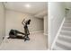 Finished basement area with neutral carpet and walls, featuring a modern elliptical machine and stairway access at 5698 Kenderly Ct, Carmel, IN 46033